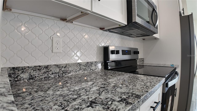 kitchen featuring stainless steel appliances, white cabinetry, and light stone countertops