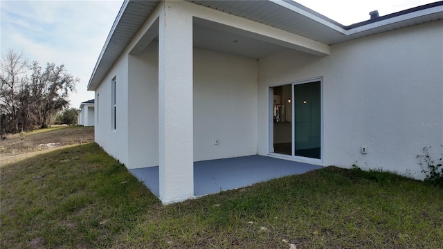 view of side of home featuring a patio area and a lawn