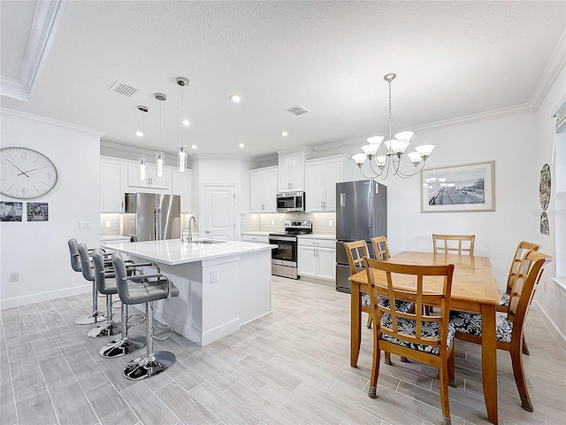 kitchen featuring a center island with sink, tasteful backsplash, hanging light fixtures, stainless steel appliances, and sink