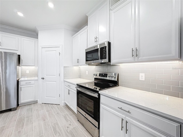 kitchen with appliances with stainless steel finishes, white cabinetry, backsplash, and light stone counters