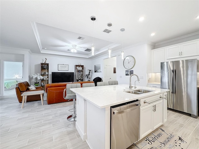 kitchen with appliances with stainless steel finishes, sink, white cabinets, and a center island with sink