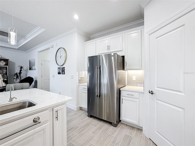 kitchen with tasteful backsplash, high end fridge, white cabinets, ornamental molding, and sink