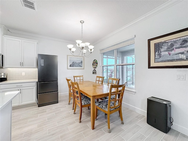 dining space featuring an inviting chandelier, a textured ceiling, and ornamental molding