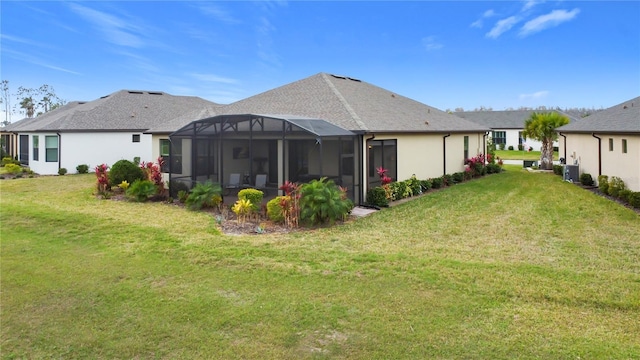 back of property with glass enclosure and a lawn