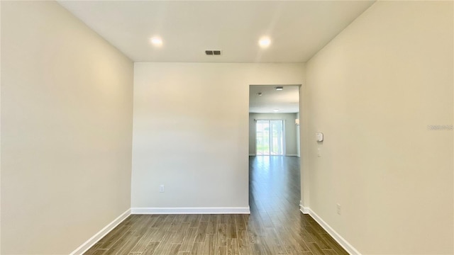 corridor featuring dark wood-style floors, visible vents, and baseboards