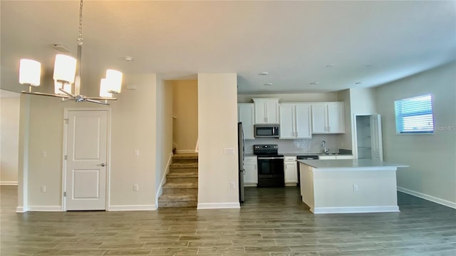 kitchen featuring black range with electric cooktop, white cabinets, light countertops, stainless steel microwave, and pendant lighting