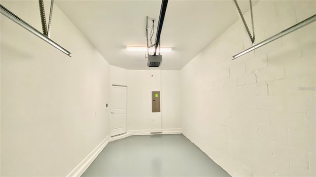 garage with baseboards, electric panel, concrete block wall, and a garage door opener