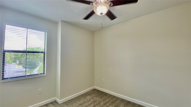 carpeted spare room with a ceiling fan and baseboards