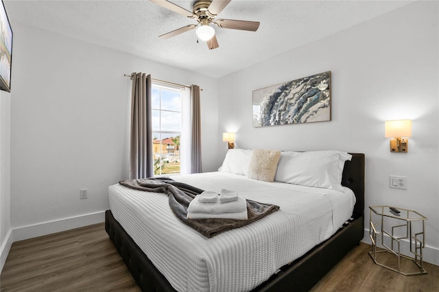 bedroom with ceiling fan, dark wood-type flooring, and a textured ceiling