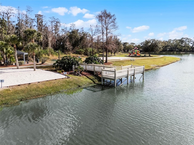 view of dock featuring a yard, a playground, and a water view