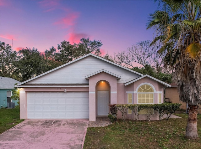 single story home with a garage, a yard, and central AC