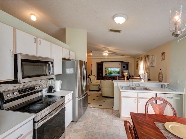 kitchen with sink, white cabinetry, vaulted ceiling, stainless steel appliances, and backsplash