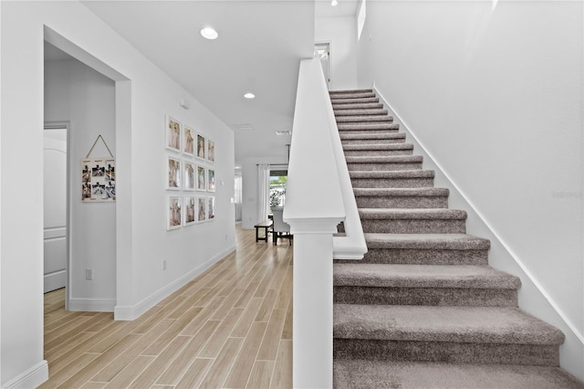 stairway featuring recessed lighting, baseboards, and wood finished floors