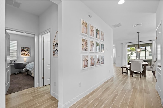 hallway with visible vents, baseboards, and wood tiled floor