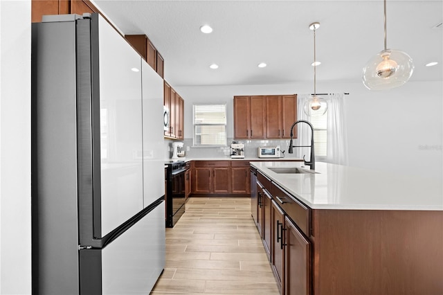 kitchen featuring a sink, decorative backsplash, light countertops, appliances with stainless steel finishes, and pendant lighting