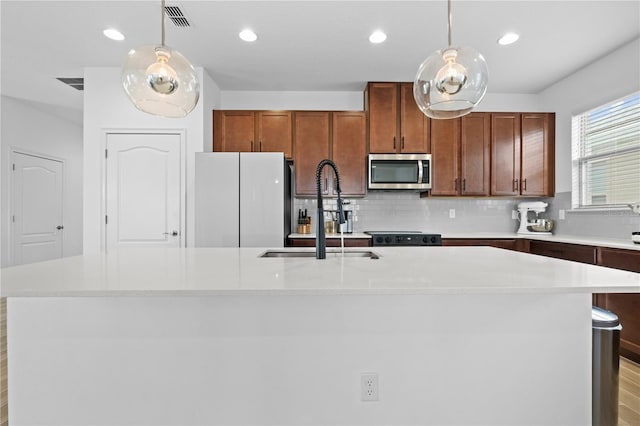 kitchen featuring a center island with sink, visible vents, a sink, light countertops, and stainless steel microwave