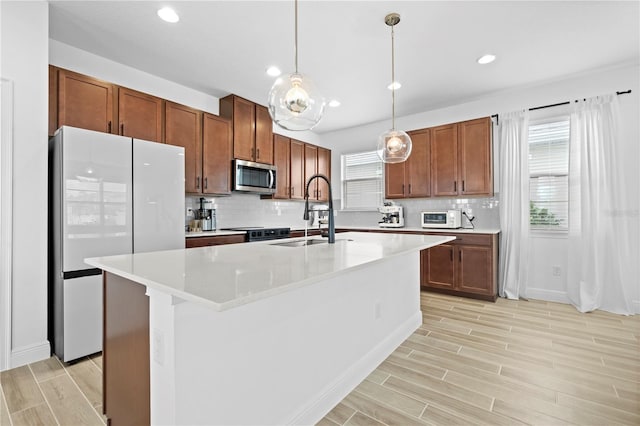 kitchen with a sink, stainless steel appliances, wood finish floors, and light countertops