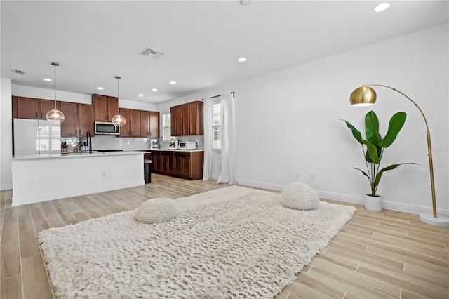 kitchen with fridge, stainless steel microwave, visible vents, and light wood-type flooring