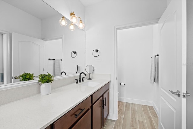 full bathroom featuring baseboards, wood tiled floor, vanity, and toilet