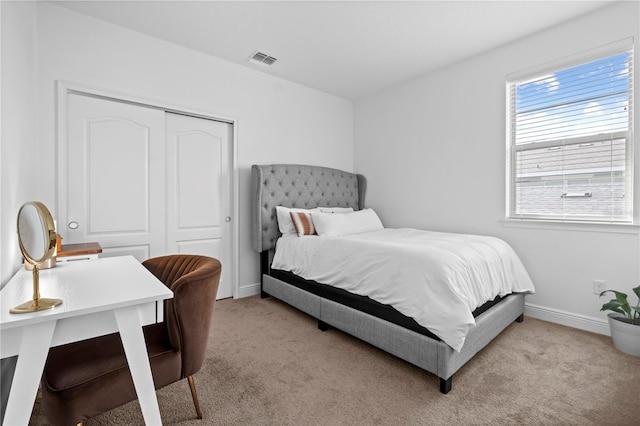 bedroom with light colored carpet, visible vents, a closet, and baseboards