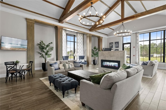 living area with a notable chandelier, a fireplace, high vaulted ceiling, and wood finished floors