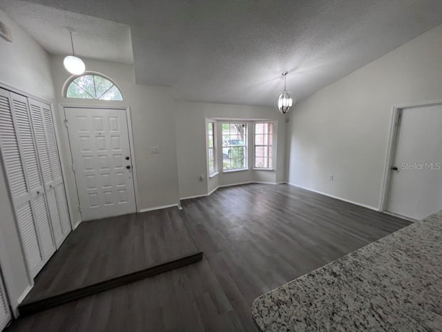 foyer entrance featuring vaulted ceiling, dark wood-type flooring, and a textured ceiling