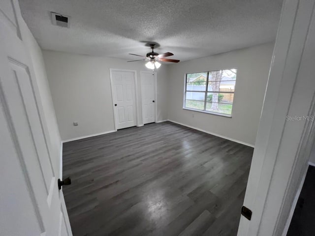 unfurnished bedroom featuring ceiling fan, dark hardwood / wood-style floors, and a textured ceiling