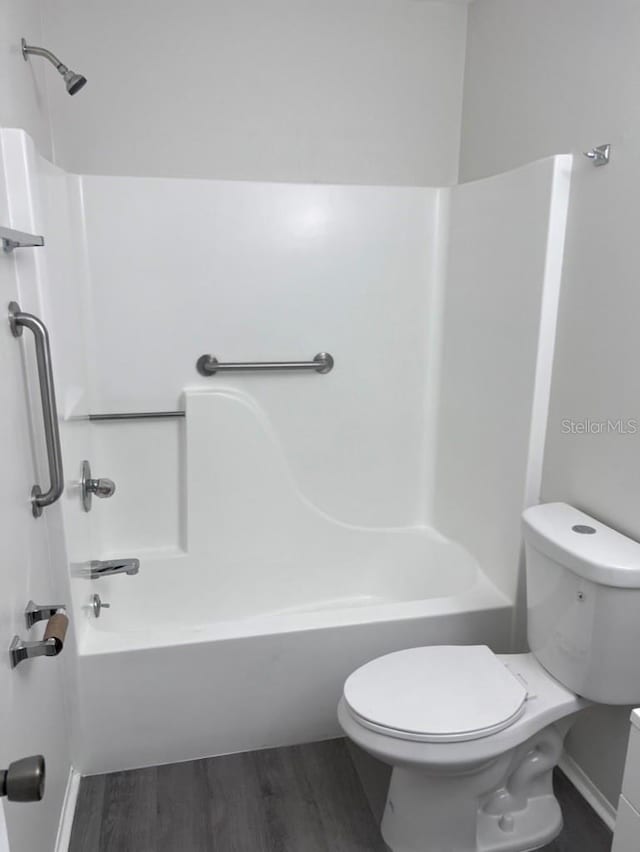 bathroom with wood-type flooring, tub / shower combination, and toilet