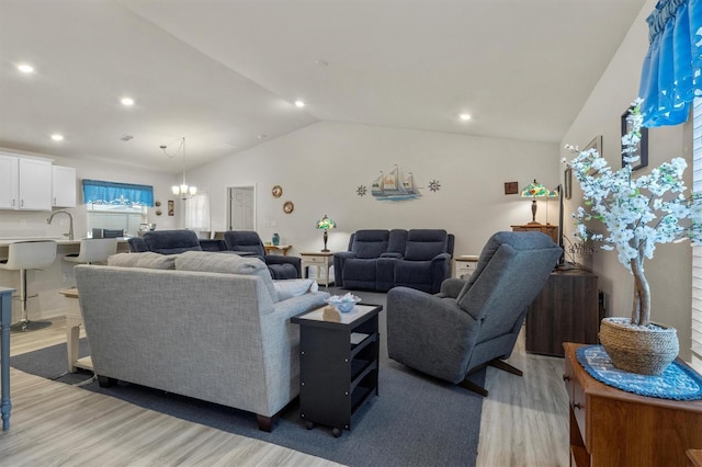 living room featuring vaulted ceiling, light wood-type flooring, a chandelier, and recessed lighting