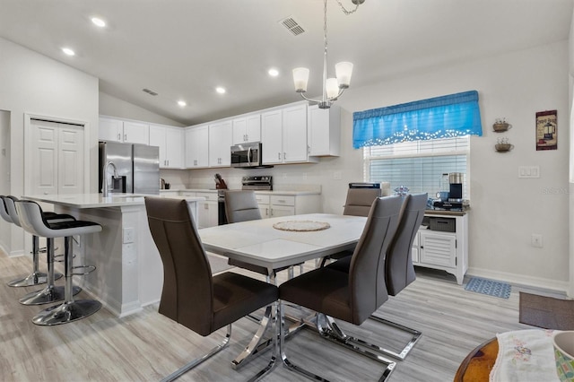 dining space featuring lofted ceiling, light wood-style floors, visible vents, and a chandelier