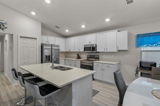 kitchen featuring a kitchen island with sink, a sink, white cabinetry, light countertops, and appliances with stainless steel finishes