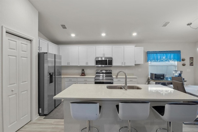 kitchen featuring visible vents, white cabinets, stainless steel appliances, light countertops, and a sink