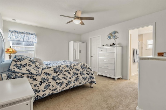 bedroom with light carpet, ceiling fan, baseboards, and connected bathroom