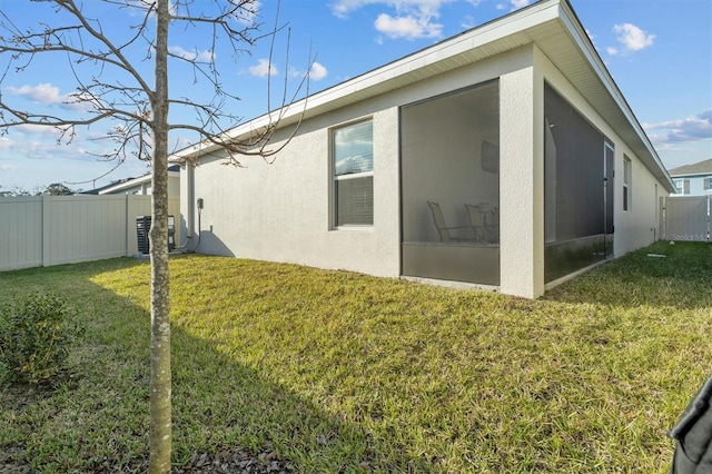 back of house with a yard, fence, a sunroom, and stucco siding