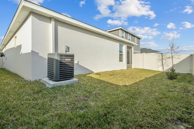 back of property featuring a yard, a fenced backyard, cooling unit, and stucco siding