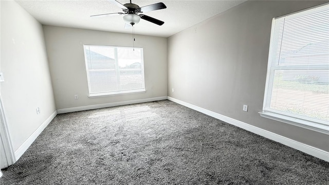 carpeted spare room with a wealth of natural light, baseboards, and a textured ceiling