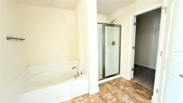 bathroom featuring a walk in closet, a shower stall, and a garden tub