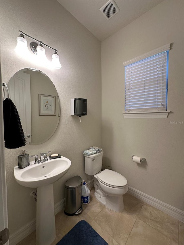 half bathroom featuring toilet, tile patterned floors, visible vents, and baseboards