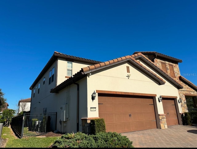 view of front of property with a garage, decorative driveway, fence, and stucco siding