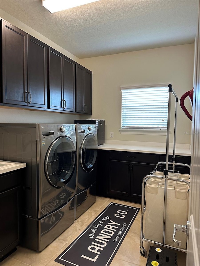 laundry room featuring a textured ceiling, light tile patterned floors, independent washer and dryer, and cabinet space