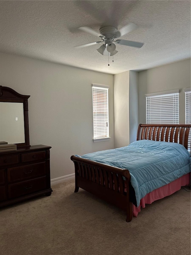 bedroom with a textured ceiling, carpet floors, a ceiling fan, and baseboards