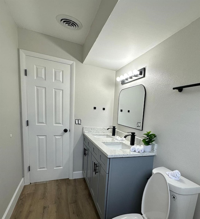 bathroom featuring double vanity, visible vents, a sink, and wood finished floors