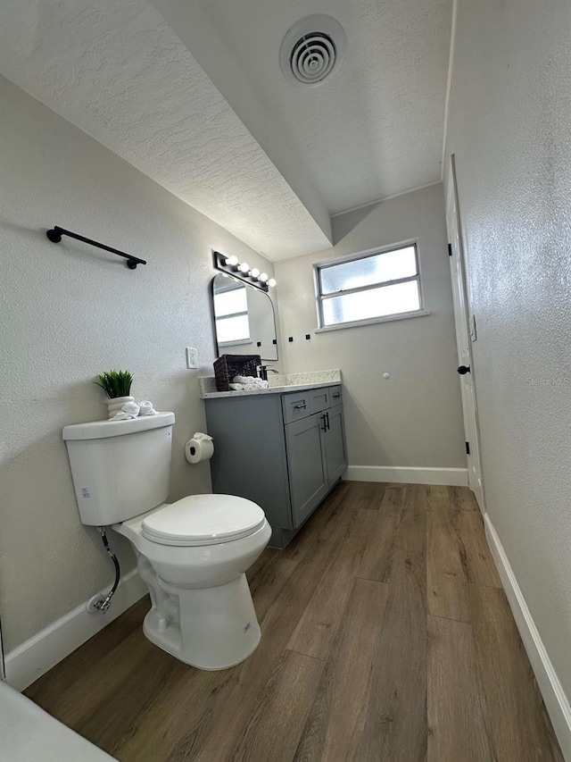 bathroom with vanity, wood finished floors, visible vents, and baseboards