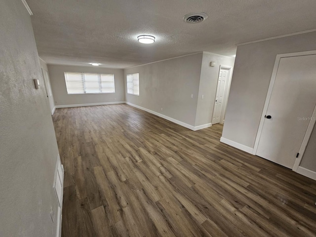 empty room featuring visible vents, dark wood finished floors, a textured ceiling, and baseboards