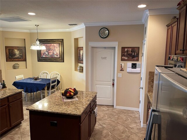1820 Trophy Bass Way, Kissimmee, FL 34746 - kitchen with light stone counters, visible vents, pendant lighting, crown molding, and washing machine and dryer