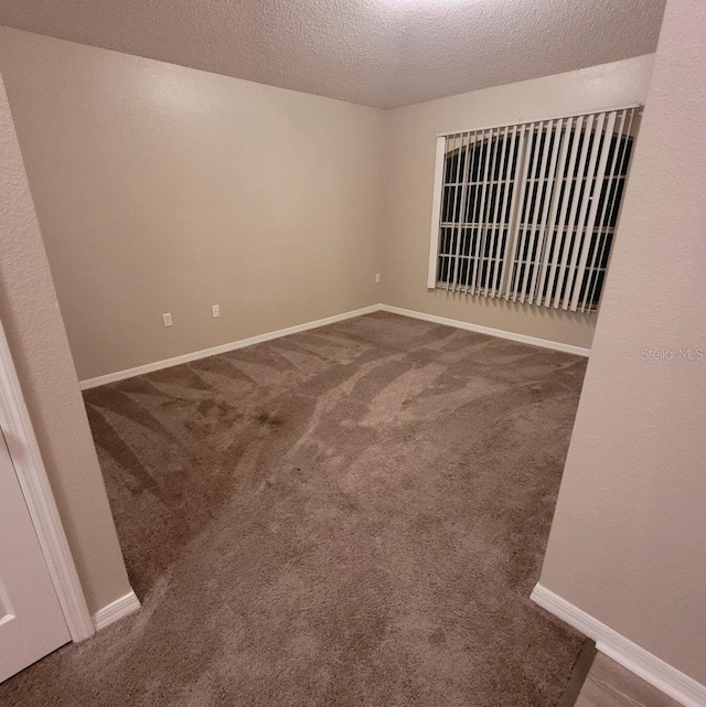 spare room featuring carpet floors, baseboards, and a textured ceiling