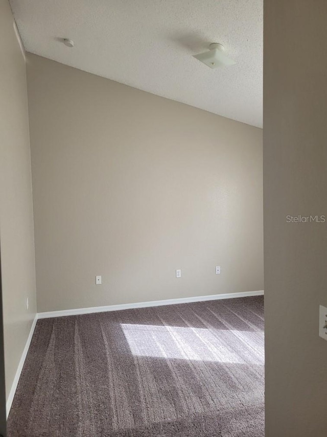 carpeted empty room with a textured ceiling and baseboards