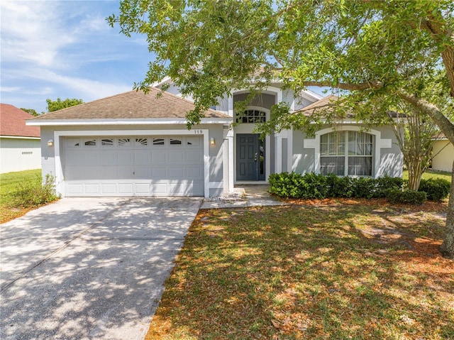 view of front of property with driveway, stucco siding, a garage, and roof with shingles