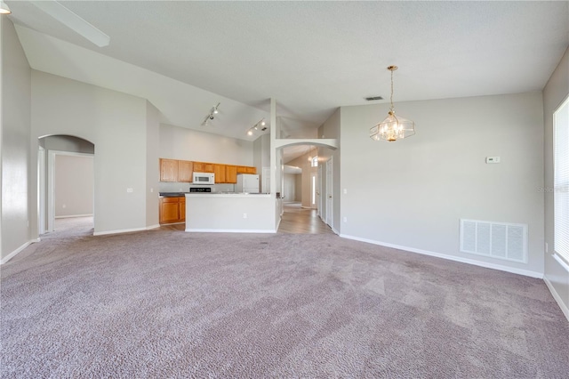 unfurnished living room featuring baseboards, a chandelier, arched walkways, visible vents, and light carpet