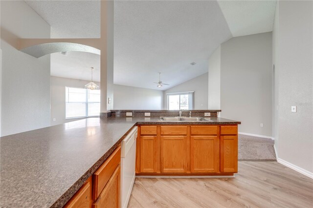 kitchen with ceiling fan with notable chandelier, a sink, dark countertops, arched walkways, and dishwasher